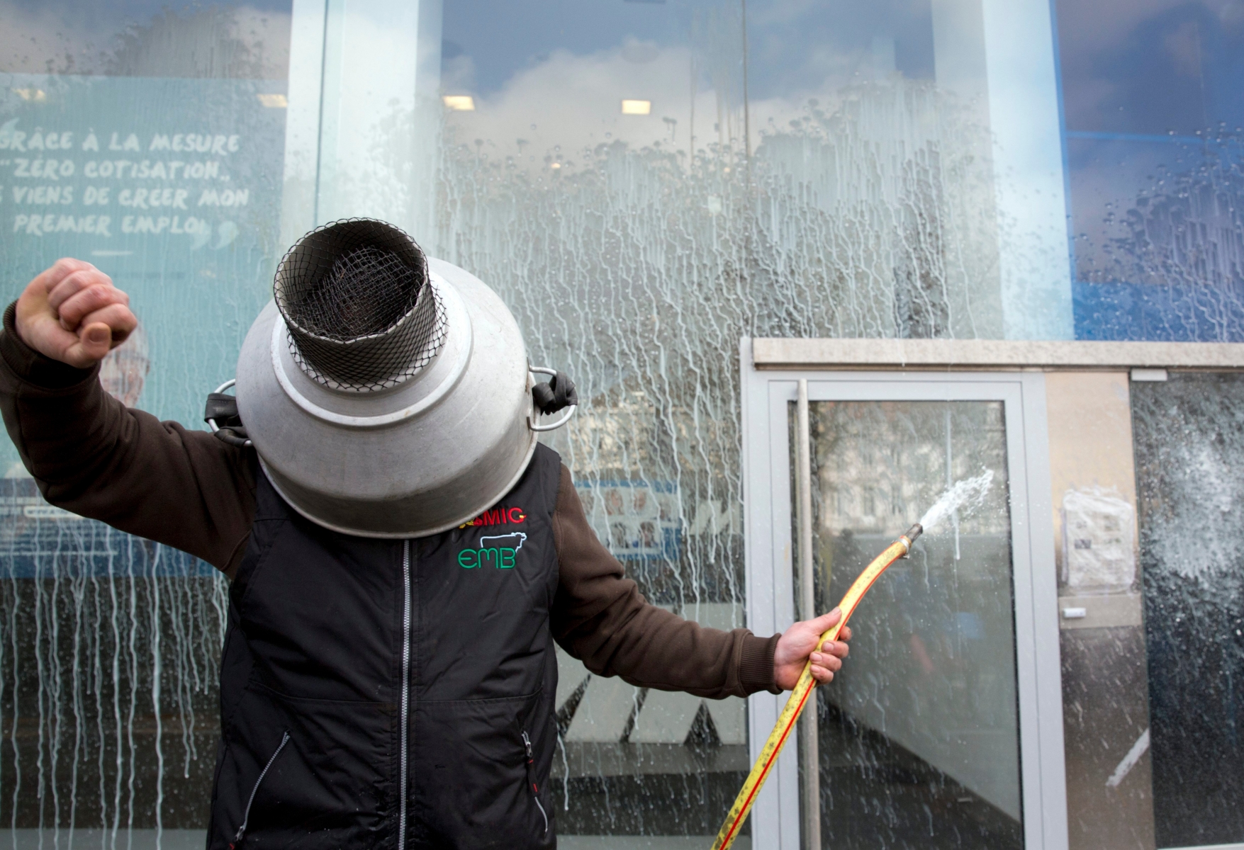 A farmer sprays milk outside the MR political headquarters during a demonstration in Brussels on Monday, March 14, 2016. Farmers demonstrated in Brussels Monday against falling food prices. Sign reads in French 'engaged for the future'. (AP Photo/Thierry Monasse) Belgium EU Farmers demonstration