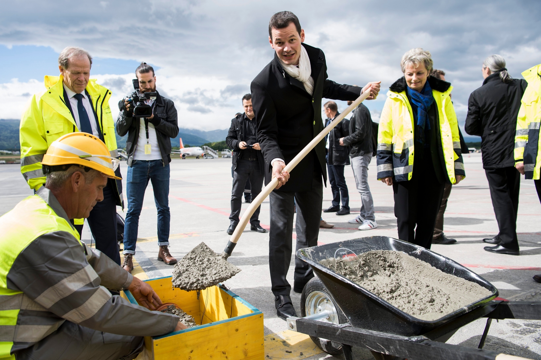 Pierre Maudet, Conseiller d'Etat genevois, depose du ciment lors de la pose symbolique de la premiere pierre du chantier de l'Aile Est de Geneve Aeroport ce jeudi 19 mai 2016 a Geneve. (KEYSTONE/Jean-Christophe Bott) SUISSE AEROPORT AILE EST
