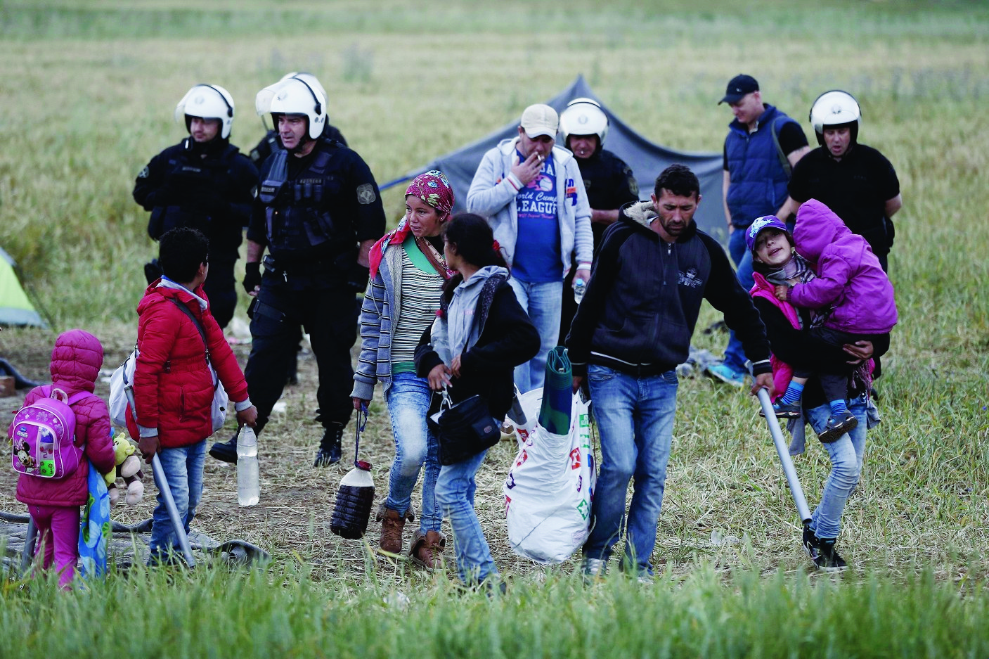 epa05325982 Members of a refugee family carry their belongings during a police operation at a refugee camp at the border between Greece and Former Yugoslav Republic of Macedonia (FYROM), near the village of Idomeni, northern Greece, 24 May 2016. The transport of refugees from Idomeni to the new accommodation centres started on Tuesday. According the refugee coordinating committee spokesman Giorgos Kyritsis, all the refugees will have been transferred in the next ten days adding that it will be a smooth relocation procedure and not a police sweeping operation.  EPA/YANNIS KOLESIDIS GREECE REFUGEES MIGRANTS SITUATION