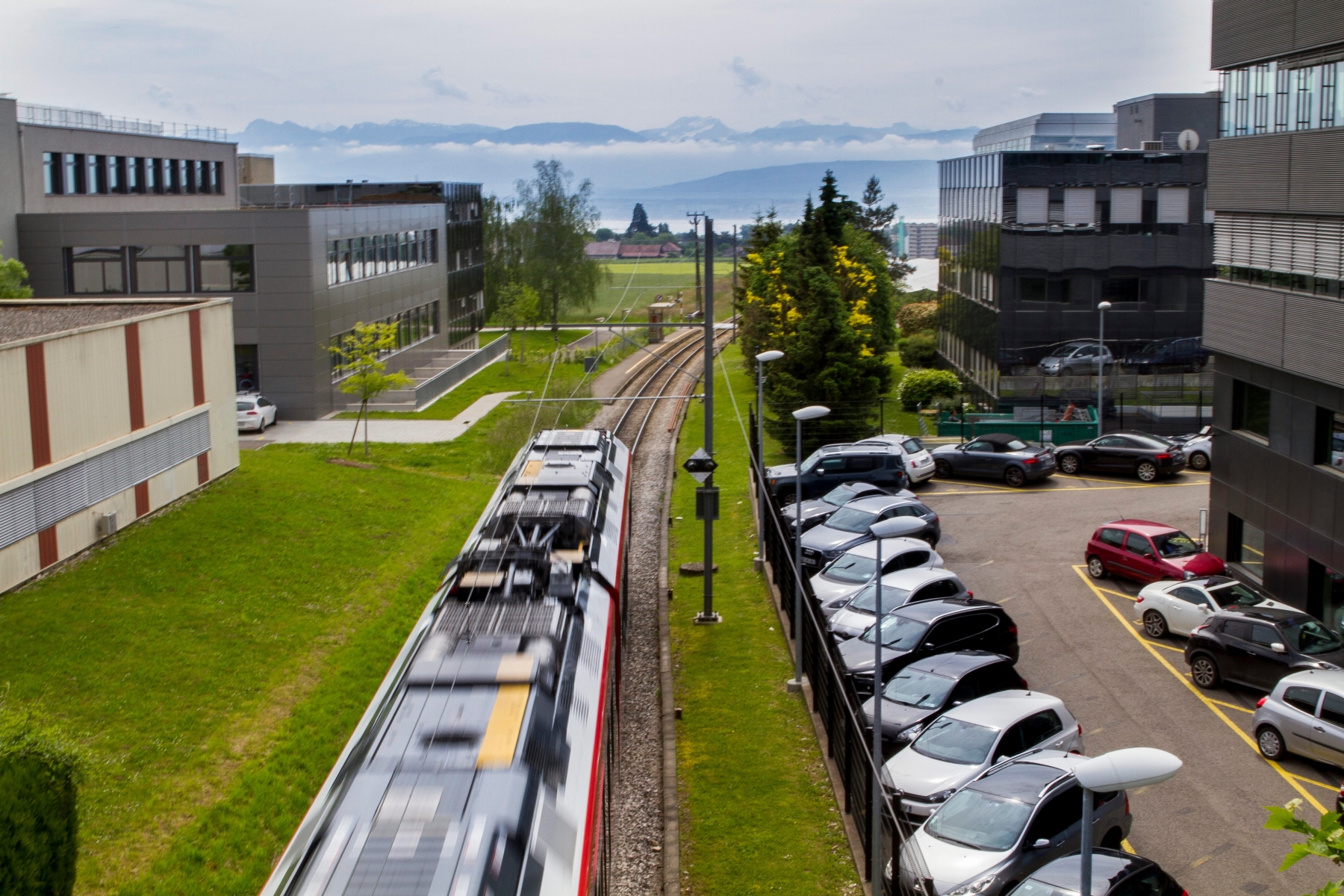 Mobilité: débat transports publics VS voitures.
Petit train ligne Nyon-St-Cergue-Morez (NStCM) d'un côté, parking de voitures de l'autre.
Jeudi 26 mai 2016, Nyon. Mobilité - Débat Transports Publics VS Voitures