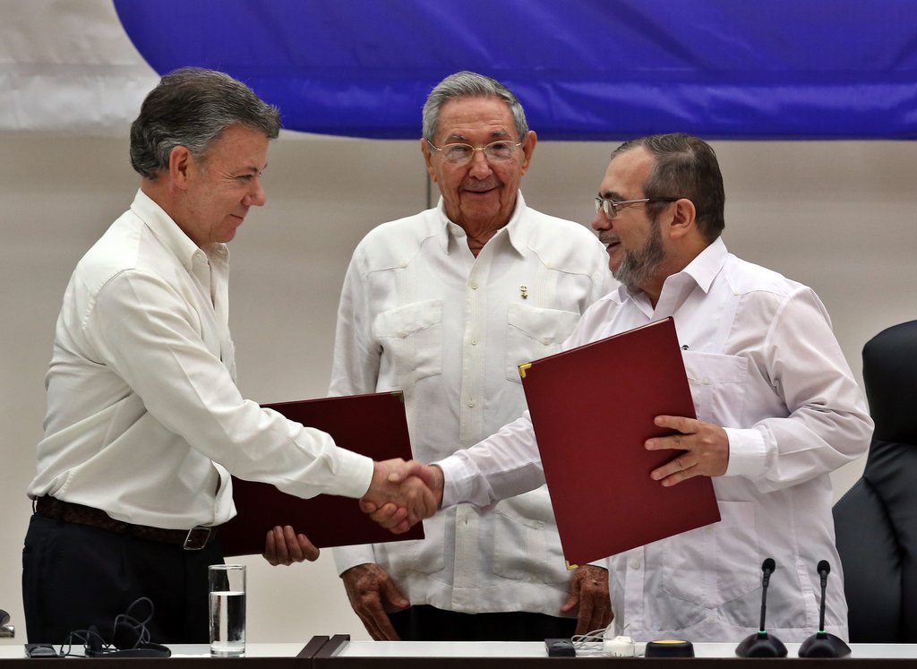 Le délégué des FARC Londono Echeverri 'Timochenko' (droite) et le président colombien Juan Manuel Santos (gauche) se sert la main en présence du président cubain Raul Castro (centre).