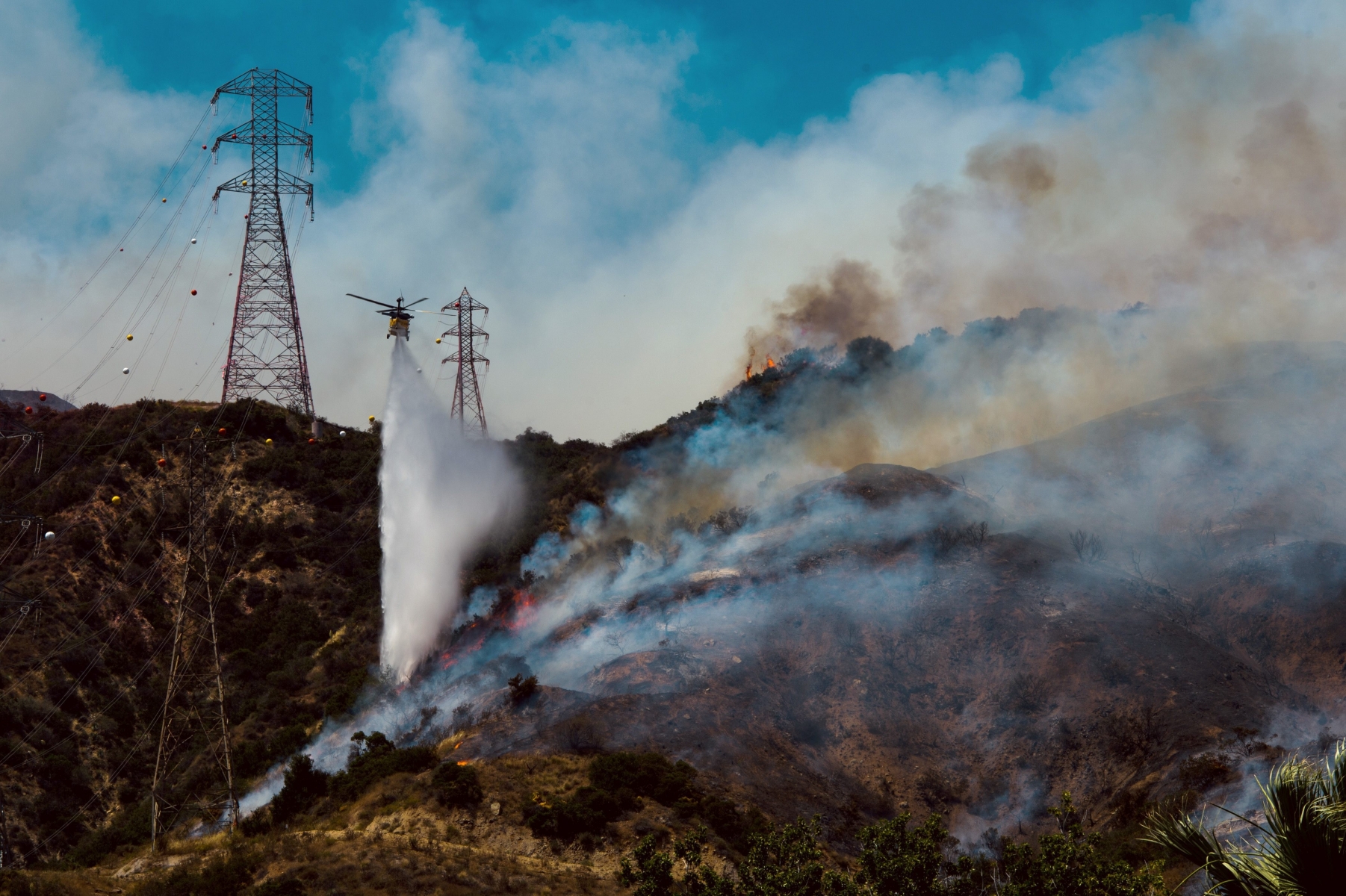A fire helicopter makes a water drop on hotspots burning in Duarte, Calif., Monday, June 20, 2016. Police in the city of Azusa and parts of Duarte ordered hundreds of homes evacuated. Others were under voluntary evacuations. (Watchara Phomicinda/San Gabriel Valley Tribune via AP) MANDATORY CREDIT Western Wildfires