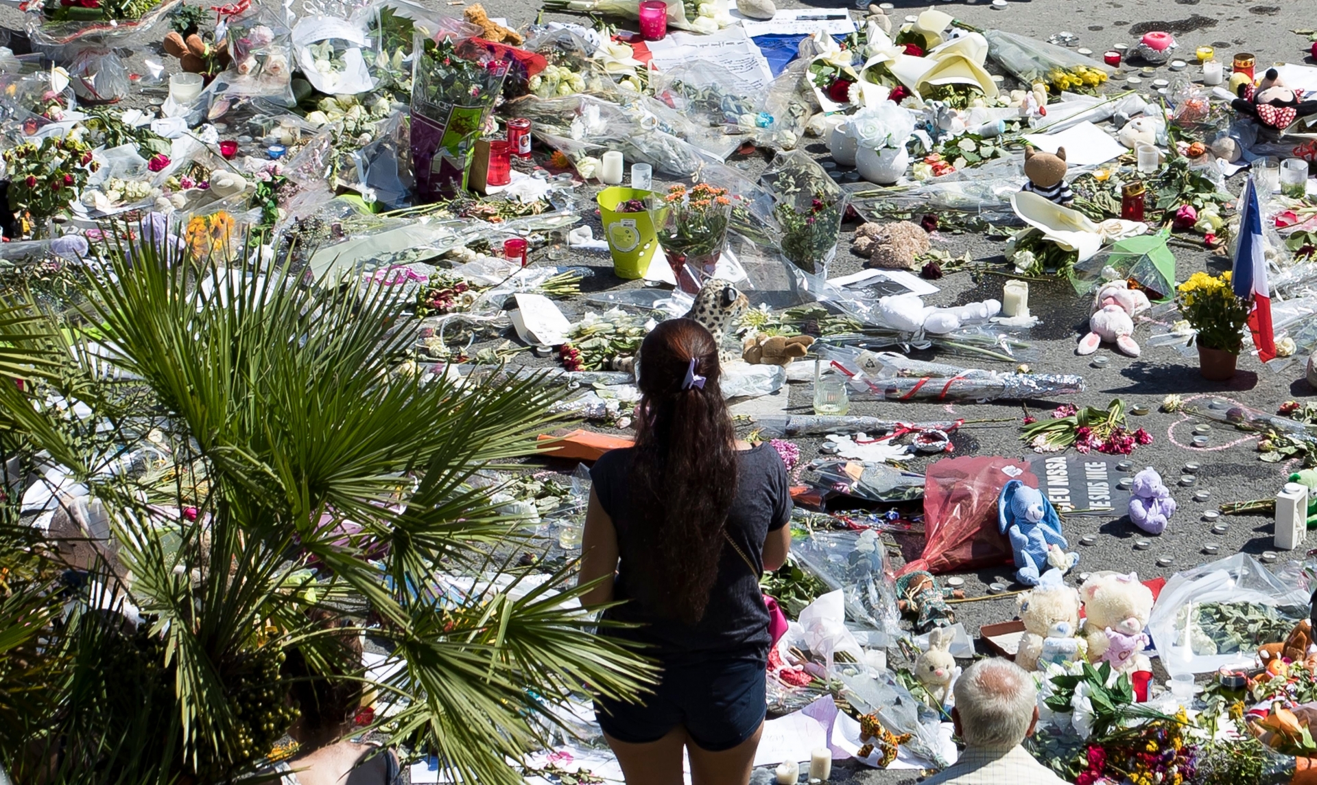 epa05429297 A woman looks at a makeshift memorial of flowers and candles on the 'Promenade des Anglais' where a truck crashed into the crowd during the Bastille Day celebrations, in Nice, France, 17 July 2016. According to reports, at least 84 people died and many were wounded after a truck drove into the crowd on the famous Promenade des Anglais during celebrations of Bastille Day in Nice, late 14 July.  EPA/IAN LANGSDON