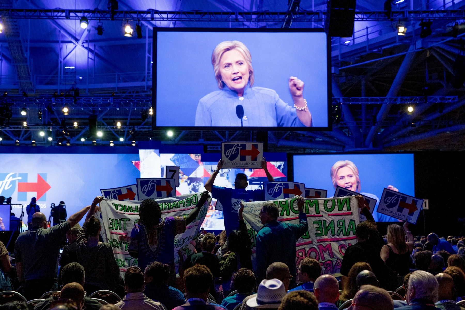 Clinton supporters try to block signs held by protesters as they disrupt Democratic presidential candidate Hillary Clinton as she speaks at the American Federation of Teachers convention at the Minneapolis Convention Center in Minneapolis, Monday, July 18, 2016. (AP Photo/Andrew Harnik) Campaign 2016 Clinton