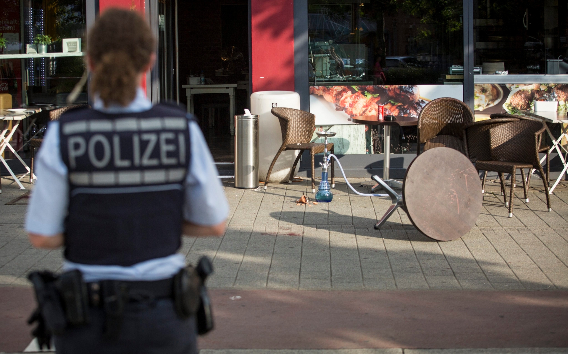 epa05439387 A policewoman in front of a cafe in Reutlingen, Germany, 24 July 2016. Nearby, a man reportedly killed a woman with a machete and injured two other people. The man was arrested. The motive of the man and his background are still unknown.  EPA/CHRISTOPH SCHMIDT GERMANY CRIME