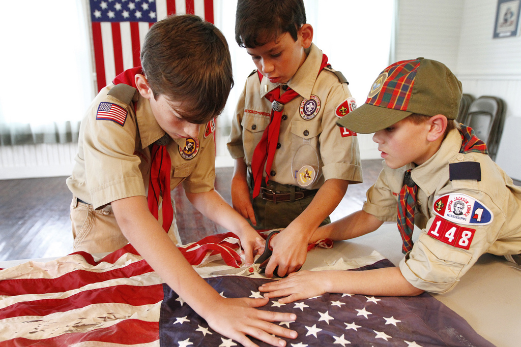 In a Thursday, June 14, 2012 photo, from the left, Boy Scouts Daniel Perkins, Caden Hollis, and Cory Culotta cut an American flag during a flag retirement ceremony at the American Legion Building in Liberty, Miss., Thursday, June 14, 2012. The flags, including three Mississippi State Flags, were cut into four pieces according to the flag retirement ceremony, making sure to keep the blue field intact as a representation that the Union will not be broken. The incineration of the pieces had to be postponed due to heavy rains coming through the area. (AP Photo/The Enterprise-Journal, Philip Hall)