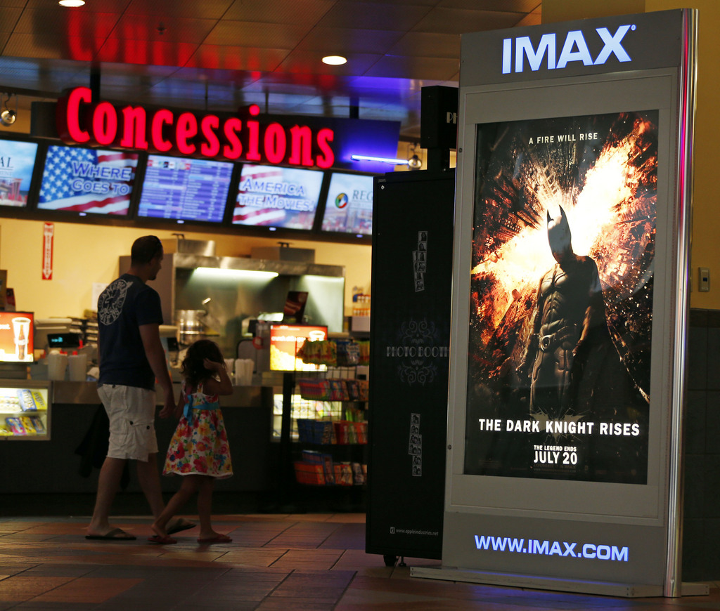 People walk past a sign for movie The Dark Knight Rises at Regal Cinemas at Crossgates Mall in Albany, N.Y., on Friday, July 20, 2012. A gunman in a gas mask barged into a crowded Denver-area theater during a midnight premiere of the Batman movie on Friday, July 20, 2012, hurled a gas canister and then opened fire, killing 12 people and injuring at least 50 others in one of the deadliest mass shootings in recent U.S. history. (AP Photo/Mike Groll)
