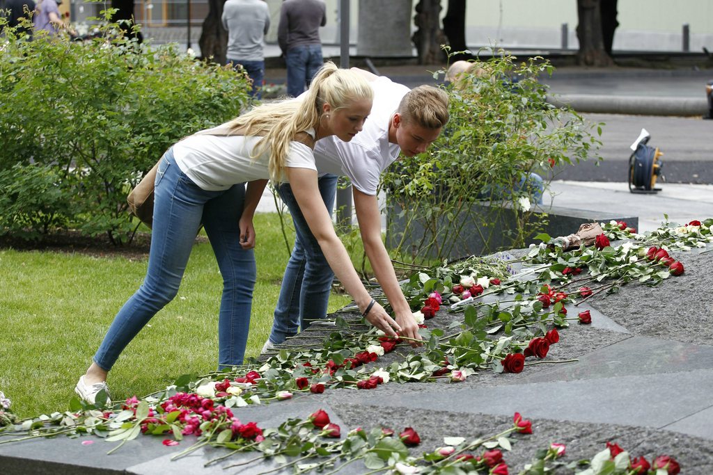 epa03314275 Two young people lay down flowers outside the damaged main government buliding in Oslo, Norway, 22 July 2012, on the first anniversary of the atrocities which took place here and at the Utoeya Island, and in which 77 people perished. 77 people were killed and 209 wounded in what is regarded as the worst act of violence in Norway since World War II. Anders Behring Breivik, who has admitted carrying it out, remains on trial, and judges are yet to decide if he is sane or not before he is sentenced.  EPA/TOR ERIK SCHROEDER NORWAY OUT
