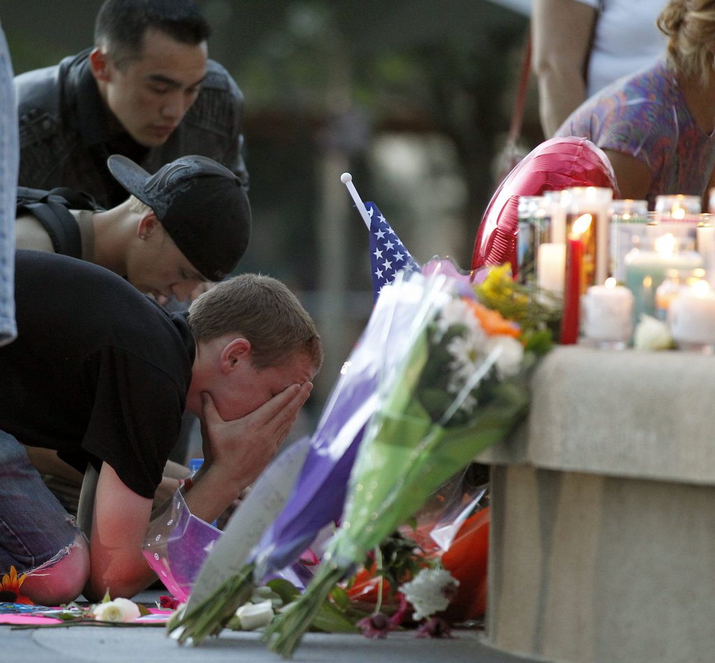 A man holds his face in his hands in front of a memorial after a prayer vigil Sunday, July 22, 2012 in Aurora, Colo. Twelve people were killed and over 50 wounded in a shooting attack early Friday at the packed theater during a showing of the Batman movie, "The Dark Knight Rises." Police have identified the suspected shooter as James Holmes, 24. (AP Photo/Alex Brandon)