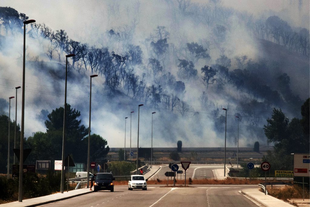 Smoke clings to the forest as flames burn the forest near the highway in La Jonquera, Spain, near the border with France, Sunday, July 22, 2012.  The regional officials said wildfires have burned almost 7,000 hectares (17.297 acres) of forest. (AP Photo/Josep Ribas)