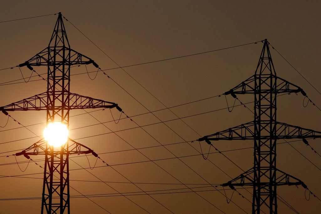 Le soleil se couche sur deux pylones electriques d'une ligne a haute tension ce samedi 13 fevrier 2010 a Sion. (KEYSTONE/Jean-Christophe Bott)