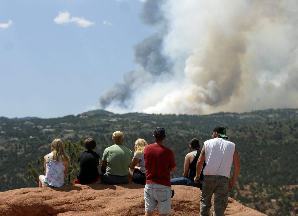 People watch as smoke billows from a wildfire west of Colorado Springs, Colo. on Saturday, June 23, 2012. The fire has grown to an estimated 600 acres and The Gazette reports authorities are evacuating the exclusive Cedar Heights neighborhood as well as the Garden of the Gods nature center. (AP Photo/Bryan Oller)