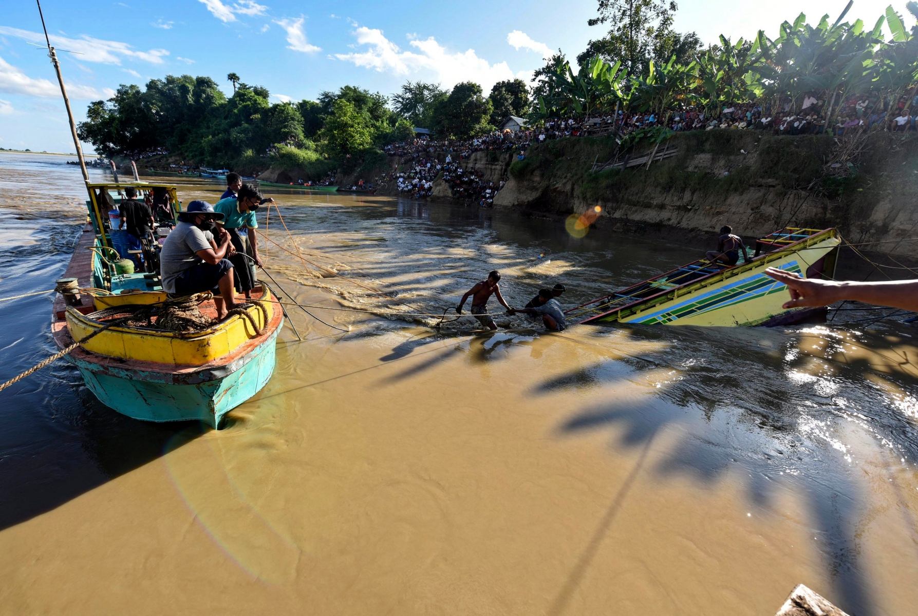 epa05590370 Local rescue workers try to pull a sunk ferry boat from the Chindwin river near the city of Monywa, Sagaing Division, Myanmar, 18 October 2016. Acoording to local sources, the death toll reached 44 while hundreds of people are still missing and are believe to be trapped inside the boat. So far 159 people survived the ferry boat accident after the vessel hit a rock in the water during a trip from Homelin to Monywa on 15 October 2016. Workers will continue to lift the boat from the riverbed on 19 October.  EPA/STRINGER MYANMAR FERRY BOAT ACCIDENT