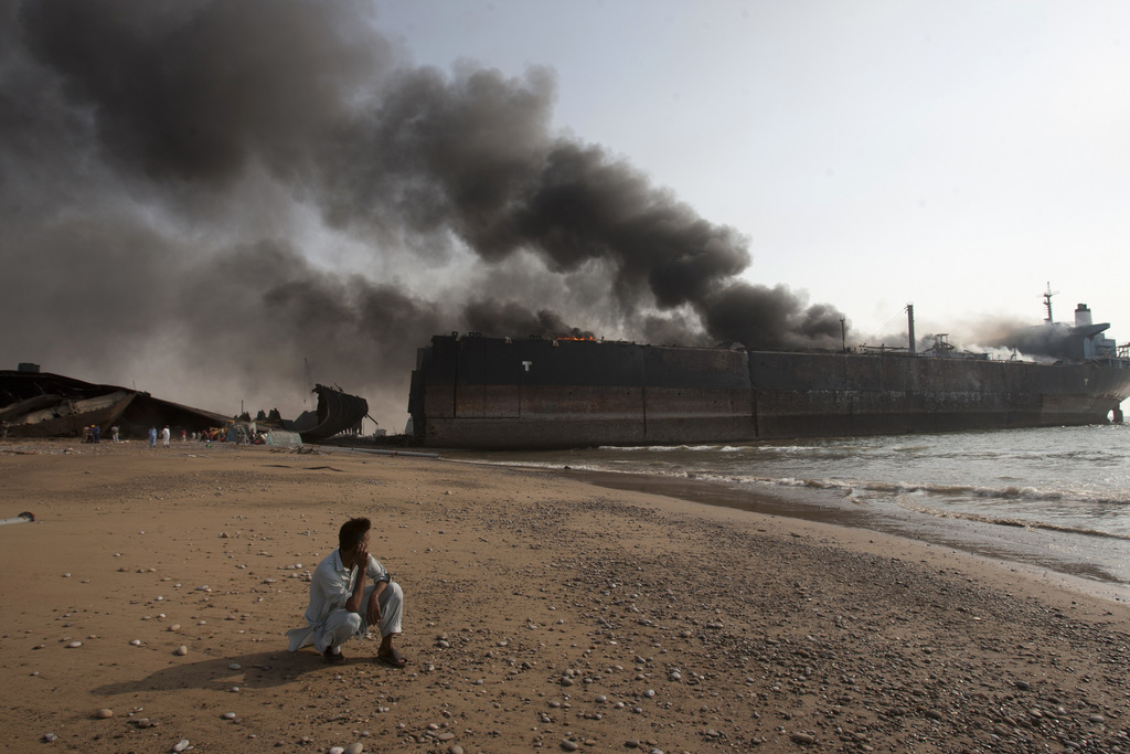 Des flammes étaient visibles sur la partie supérieure de l'énorme navire, ancré au bord de la plage, et il s'en échappait d'épaisses colonnes de fumée noire.