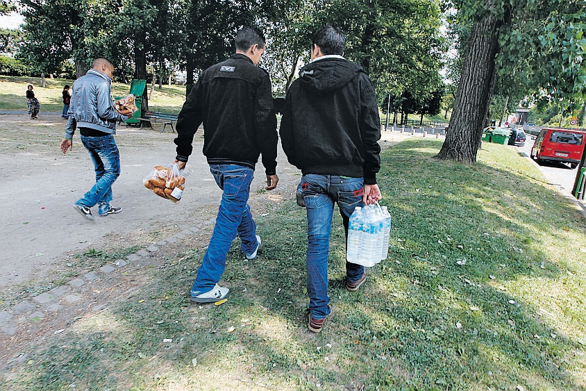 Des immigrés tunisiens réfugiés dans le square de la rue du Chemin-de-fer dans le XIX ème arrondissement, derrière la porte de la Villette. Ici, deux hommes rapportent des petits pains et des bouteilles d'eau. 100902