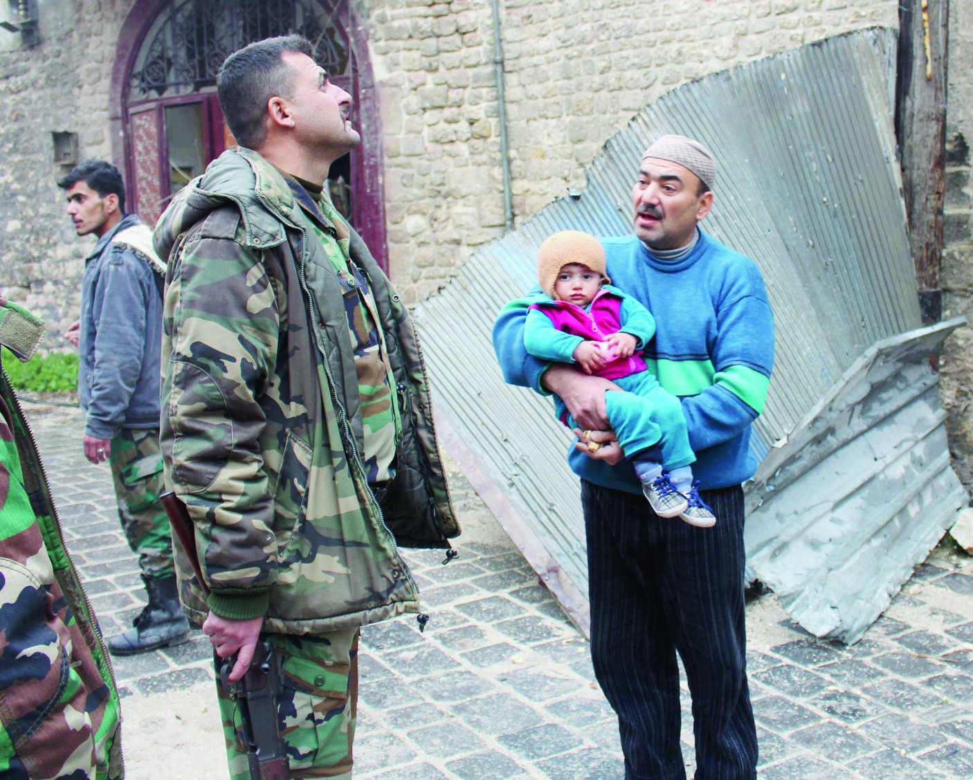 epa05674364 A a father holding his son talks with a Syrian soldier in the old markets of the eastern neighborhoods of Aleppo, Syria, 13 December 2016. According to media reports, the army holds 99 percent of Aleppo's eastern neighborhoods. The Syrian military's media arm said that Aleppo would be announced as a safe liberated city following the exit of buses carrying gunmen from al-Ramousseh to al-Rashideen 4 in the west of Aleppo, which is still under the armed groups' control.  EPA/STRINGER  EPA/STRINGER SYRIA CONFLICT ALEPPO BATTLE