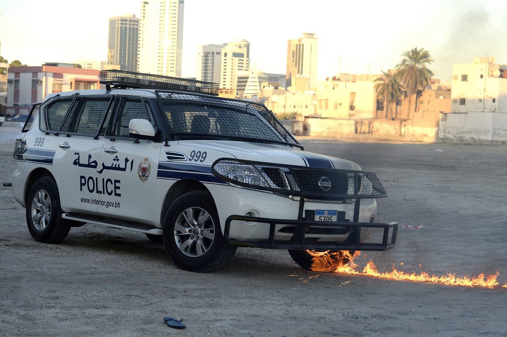 epa03975588 The tyres of a police car catches fire during clashes with protesters following the third day of the funeral for 15-year-old Ahmed Abdul-Ameer in Sanabis village, a suburb of the Bahraini capital Manama 03 December 2013. Heavy clashes broke-out between mourners and police following the third day of the funeral for 15-year-old Ahmed Abdul-Ameer who died 30 November 2013 following burn injuries he sustained while protesting. The youth death had sparked clashes in several areas across Bahrain and comes amid increasing tension as reconciliation talks in the Gulf island fail to resume.  EPA/MAZEN MAHDI