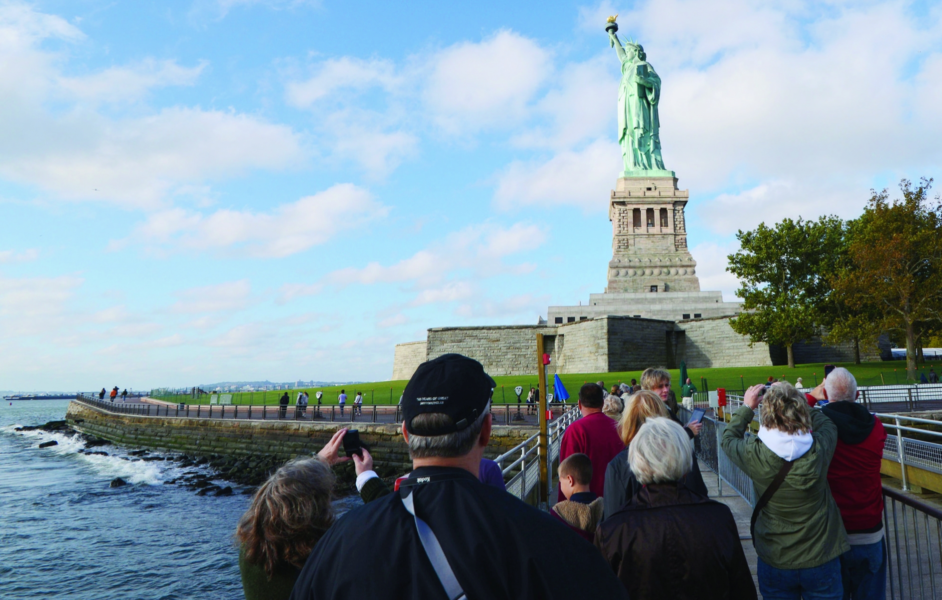 epa03908657 Tourists take pictures of the reopened Statue of Liberty, on Liberty Island in New York City, New York, USA, 13 October 2013. Four US states will pay the federal government to keep their major tourism attractions open for visitors. Arizona, South Dakota, Utah and New York state have agreed to pay the National Park Service to reopen locations that have been closed since the partial US government shutdown commenced on 01 October.  EPA/PETER FOLEY USA STATUE OF LIBERTY REOPENS