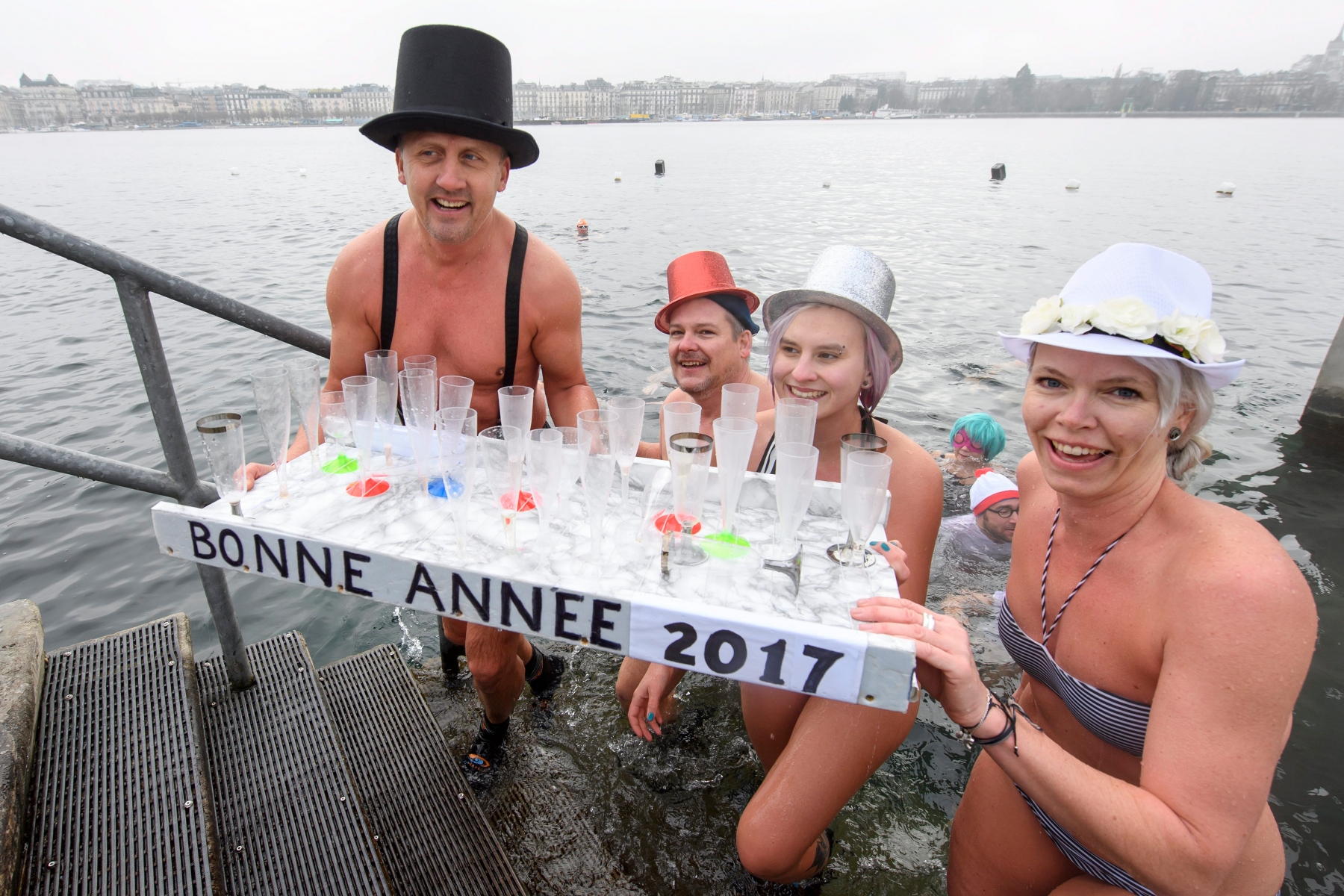 People celebrate with champagne glasses in the cold water (6,8 degrees) of Lake Geneva, during the New Year's traditional swim, in Geneva, Switzerland, on Sunday, January 1, 2017. Around 50 swimmers took part in the 23th edition of the traditional swim to mark the New Year. (KEYSTONE/Martial Trezzini) SCHWEIZ NEUJAHR 2017 NEUJAHRSSCHWIMMEN