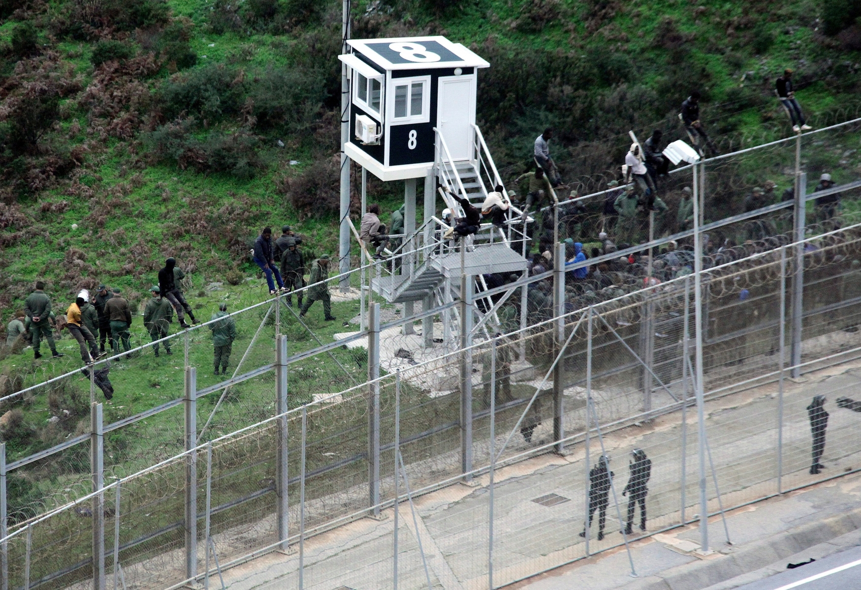 epa05694908 (FILE) - A file photograph showing Moroccan Police looking at immigrants trying to jump the six-meter-high fence in Ceuta, Spanish enclave on the north of Africa, 09 December 2016. Media reports on 02 January 2017 state that more than 1,100 African migrants attempted to storm a border fence in Ceuta injuring fifty Moroccans and five Spanish border guards. Only two migants made it across the border but both needed hospital treatment following their breach.  EPA/REDUAN (FILE) SPAIN MIGRATION CEUTA