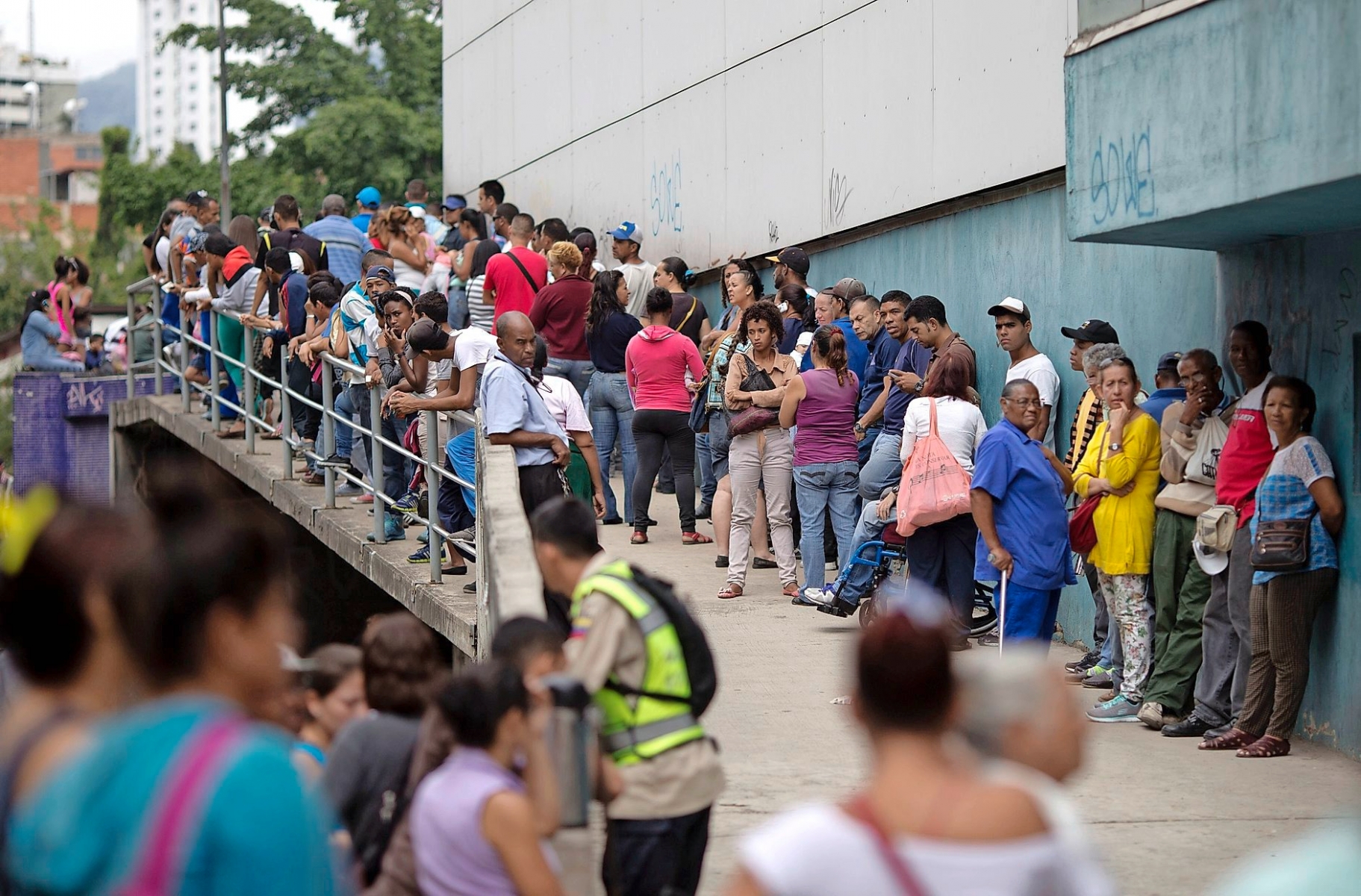 In this Nov. 18, 2016 photo, people wait outside a supermarket to buy government subsided food in Caracas, Venezuela. As domestic production dries up in Venezuela, the state has given itself the role of importing nearly all the country's food. (AP Photo/Ariana Cubillos) Venezuela Undone Profiting From Hunger