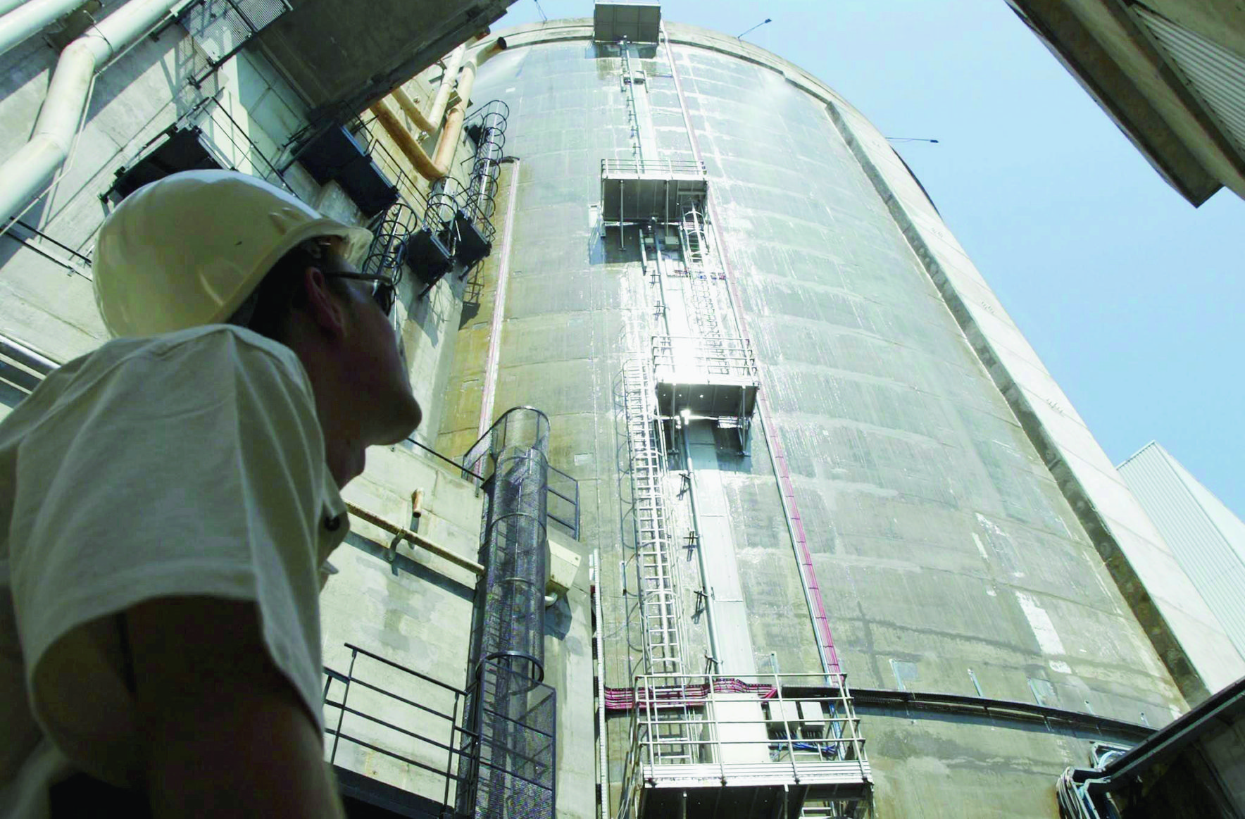 A man looks at the reactor tower that is being sprayed with cold water at the nuclear plant of Fessenheim, eastern France, Monday, 04 August 2003. The measure was taken in order to keep the temperatures inside the building at a normal level despite the heat wave sweeping the country. The initiative is part of a series of test of cooling techniques going on since Friday, but officials at the plant are unable to say whether it works. (KEYSTONE/EPA/SIPA/CHRISTIAN HARTMANN) FRANCE NUCLEAR WEATHER