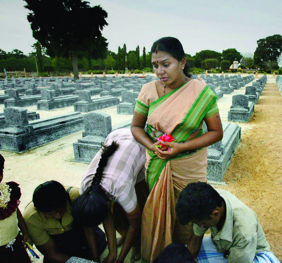 A Tamil woman pays tributes to her brother, at the Liberation of Tamil Tiger Eelam or LTTE martyr's graveyard, on the outskirts of Kilinochchi, 328 kilometers,(205 miles) north of Colombo, Sri Lanka, Tuesday June 20, 2006.  At Tamil Eelam's heart lies Kilinochchi, a town that seems like it could be swallowed by the bush and forest that surrounds it. Mildew stains the sides of buildings, many of them pockmarked with bullet holes. The tallest building is four stories. Monuments to "martyrs" _ Tigers killed in the war _ dot the town. (KEYSTONE/AP Photo/Manish Swarup) SRI LANKA TIGER COUNTRY