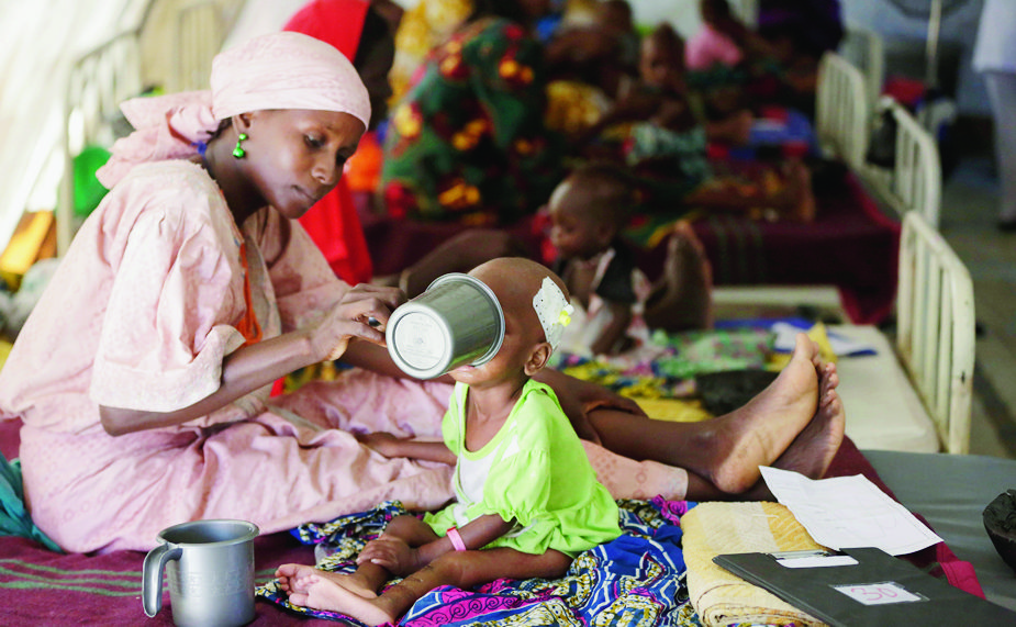 FILE - In this Monday, Aug. 29, 2016 file photo, a mother feeds her malnourished child at a feeding centre run by Doctors Without Borders in Maiduguri, Nigeria. The United Nations children's agency warned Tuesday, Feb. 21, 2017 that almost 1.4 million children are at "imminent risk of death" as famine threatens parts of South Sudan, Nigeria, Somalia and Yemen. (AP Photo/Sunday Alamba, File) Africa Famine