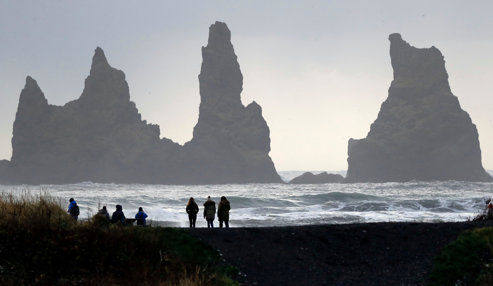 People walk on the black sanded beach in Vik, Iceland, near the Volcano Katla, Wednesday, Oct. 26, 2016. Katla Volcano has helped turn sleepy Vik, a community of 300 people some 110 miles (180 kilometers) east of the capital, Reykjavik, into a tourism hotspot. (AP Photo/Frank Augstein) ICELAND UNDER THE VOLCANO