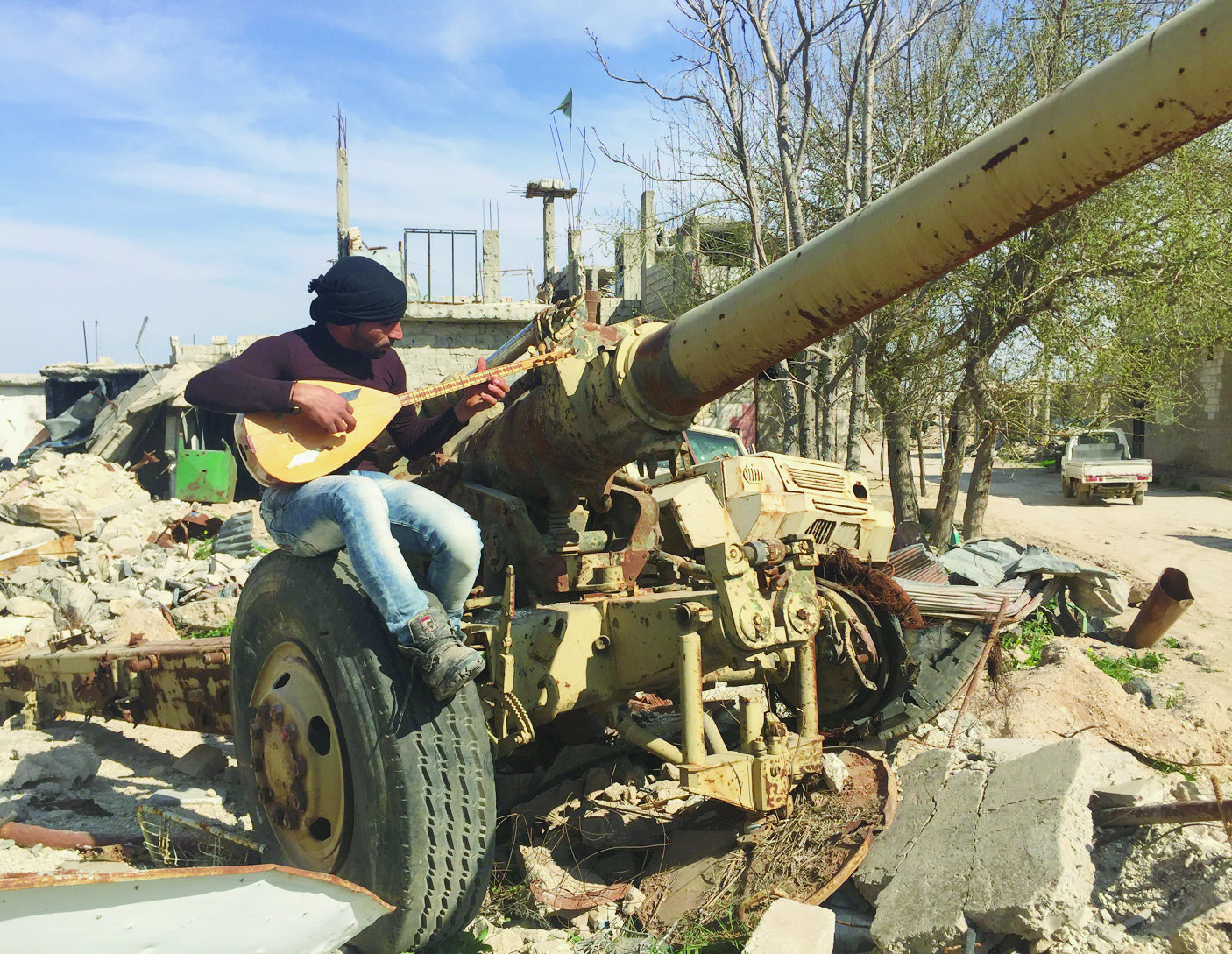 epa05875799 A photograph made available on 28 March 2017 showing a man playing a musical instrument sitting on destroyed military hadware amongst the rubble in Kobani, the Kurdish region in the Aleppo Governorate in northern Syria, 26 March 2017. US and coalition military forces continued to attack the Islamic State (IS) of Iraq and Syria, conducting 30 strikes consisting of 72 engagements against ISIS targets 27 March 2017, Combined Joint Task Force Operation Inherent Resolve officials reported on 28 March 2017.  EPA/STRINGER SYRIA CONFLICT