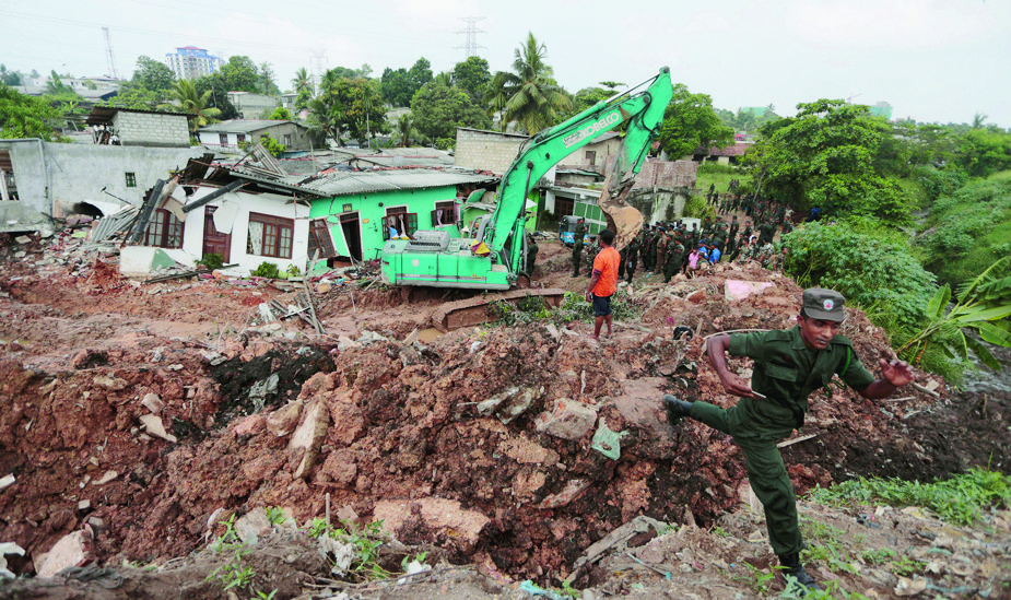 Sri Lankan army soldiers and rescue workers stand near buried houses in a collapse of a garbage dump in Meetotamulla, on the outskirts of Colombo, Sri Lanka, Saturday, April 15, 2017. A part of the garbage dump that had been used in recent years to dump the waste from capital Colombo collapsed destroying houses, according to local media reports. (AP Photo/Eranga Jayawardena) Sri Lanka Garbage Dump Collapse