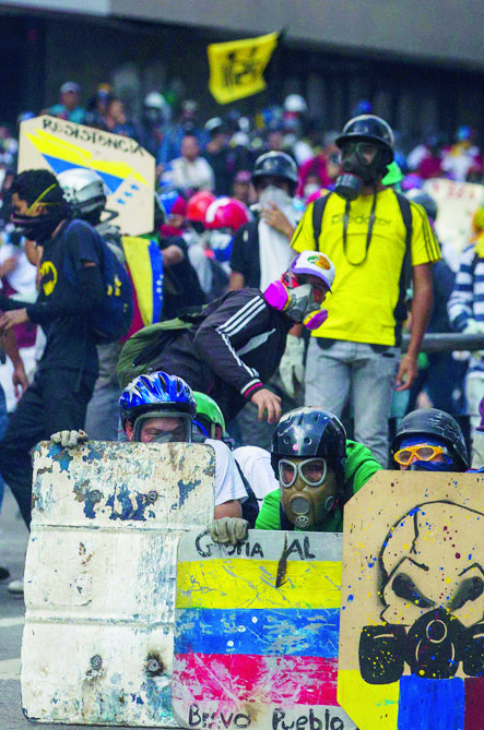 epa05977866 Protesters take cover behind makeshift shields as they clash with members of the Bolivarian National Guard (GNB) during an anti-government march in Caracas, Venezuela, 20 May 2017. Venezuelan security forces used tear gas to disperse demonstrators who were trying to reach the headquarters of the Interior Ministry, in the city center. Anti-government demonstrators have led protests against Venezuelan President Nicolas Maduro for 50 days paralyzing the divided country. At least 47 people died in violence related to the protests, media reported.  EPA/CRISTIAN HERNANDEZ VENEZUELA CRISIS