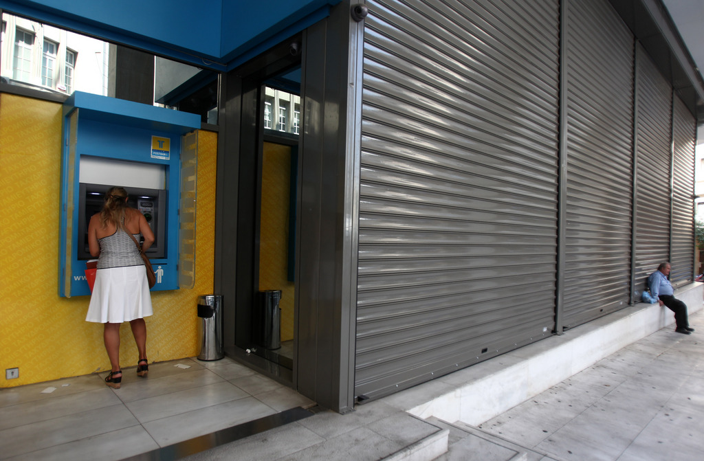 A customer at a bank machine of Hellenic Post Bank in Athens, Monday, June 30, 2012.  Bank workers on Monday held a 24-hour strike to protest cuts under Greece austerity program. (AP Photo/Thanassis Stavrakis)