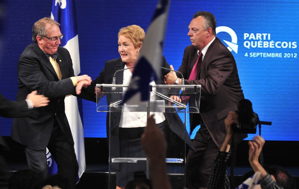 Parti Quebecois Leader Pauline Marois is whisked off stage as she delivered her victory speech in Quebec, Tuesday Sept. 4, 2012. With the win, Marois becomes the first female premier in Quebec history. Police were not immediately able to provide details but party organizers informed the crowd that there had been an explosive noise and they needed to clear the auditorium. Police say one man was arrested and two people were injured.  (AP Photo/Paul Chiasson, The Canadian Press)