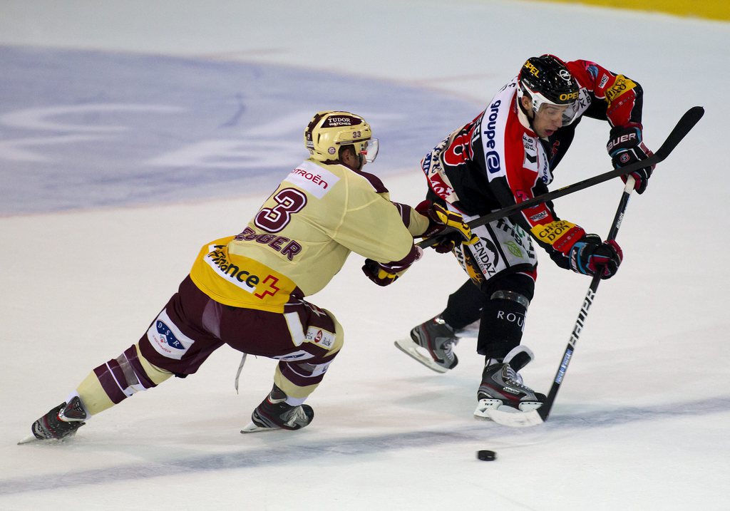 Le Servettien Gian-Andrea Randegger, à gauche, est à la lutte avec Romain Loeffel lors de la rencontre de ce soir entre Fribourg-Gottéron et Genève Servette.