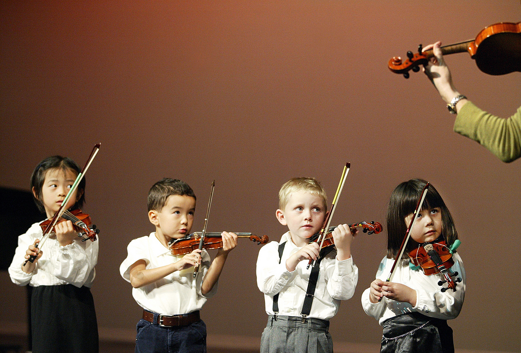 Three-year-old violin students look to their teacher as they put on a demonstration for an audience at the Fulton Performing Center on The Overlake School campus in Redmond, Wash., Sunday, May 16, 2004. The "Pre-Twinkle" violinists, as they are called by their teachers, were part of a larger concert of about 100 young violinists, up to age 18, put on by students of private teachers of the Suzuki method from around the Seattle area.  (KEYSTONE/AP Photo/King County Journal, Matt Brashears)