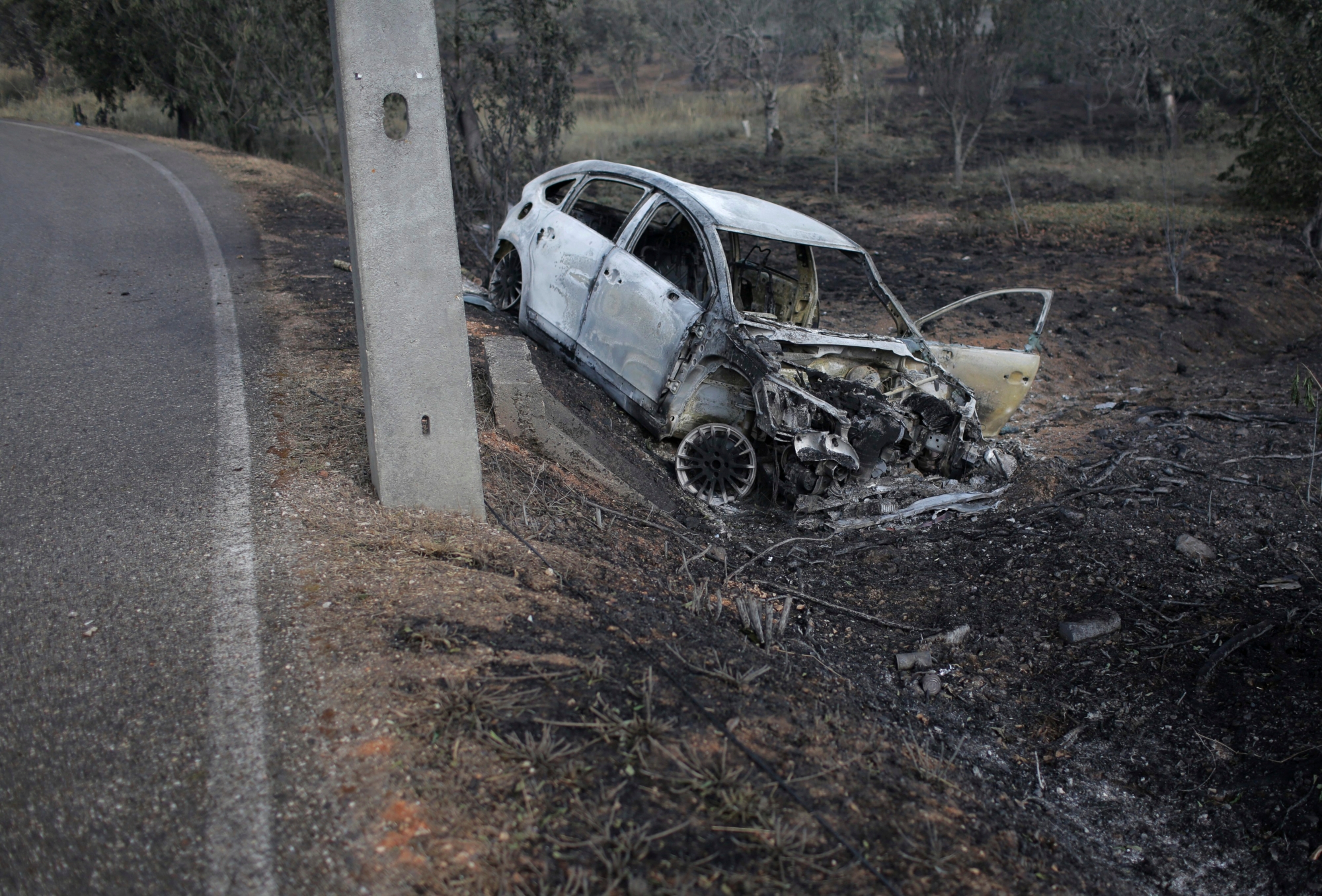 A burnt car lies where it went off the road in the village of Nodeirinho, near Pedrogao Grande, central Portugal, Monday, June 19 2017. At least 11 people were killed in the village Saturday when it was swept by a forest fire. Raging forest fires in central Portugal killed at least 62 people, many of them trapped in their cars as flames swept over roads Saturday evening. (AP Photo/Armando Franca) Portugal Forest Fires