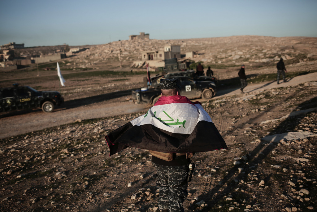 A member of the Iraqi federal police wears an Iraqi flag around his shoulders before going to battle against the Islamic State group, in Hamam al-Alil, Iraq, Sunday, Feb. 2017. U.S.-backed Iraqi forces launched a large-scale military operation on Sunday to dislodge Islamic State militants from the western half of Mosul city on Sunday. (AP Photo/Bram Janssen)