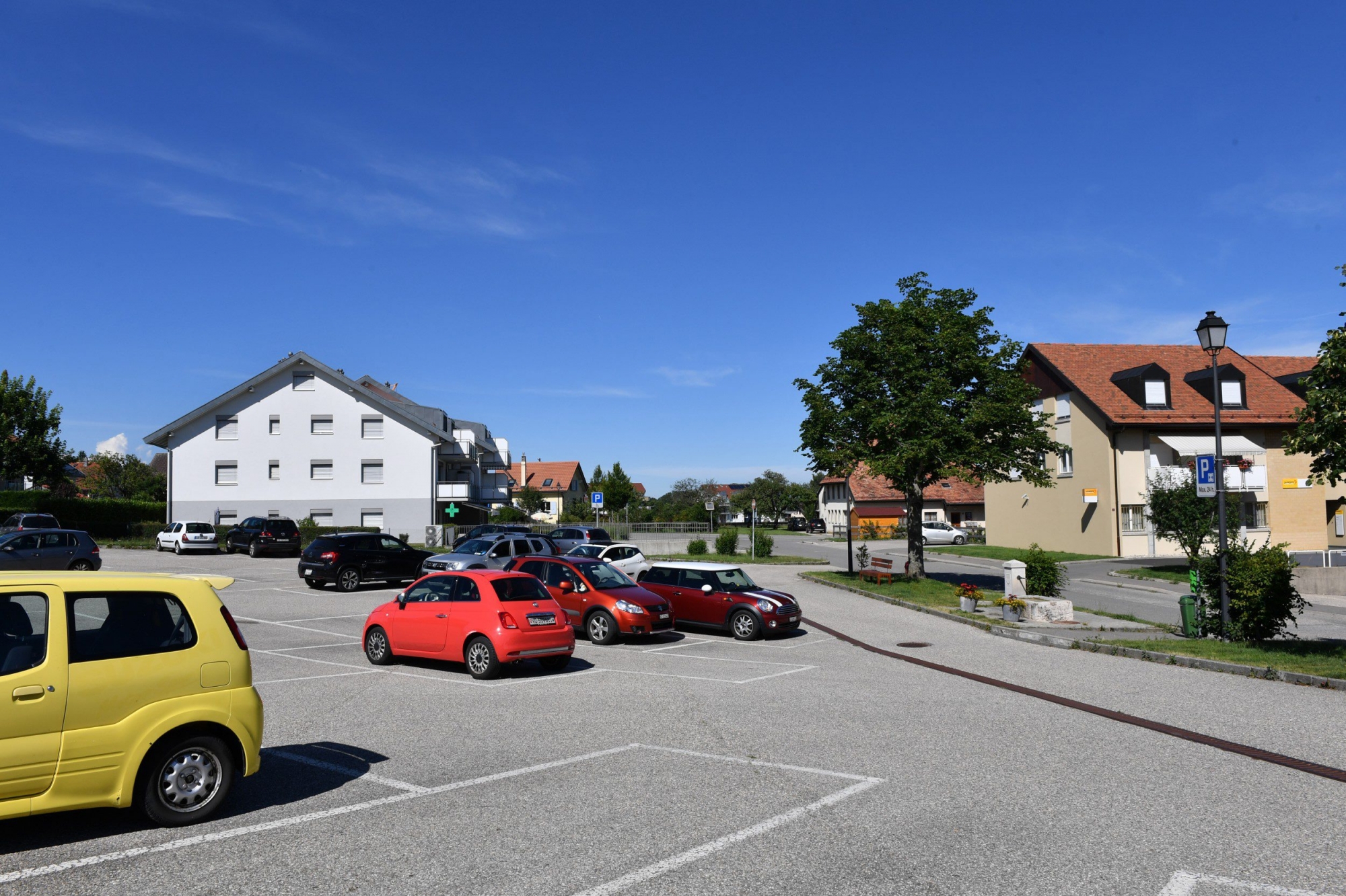 Parking du centre du village a proximité de la poste de la pharmacie et de la Banque Raiffeisen Gimel le 6.7.2017 © photo Michel Perret Parking_Gimel_6_7_2017