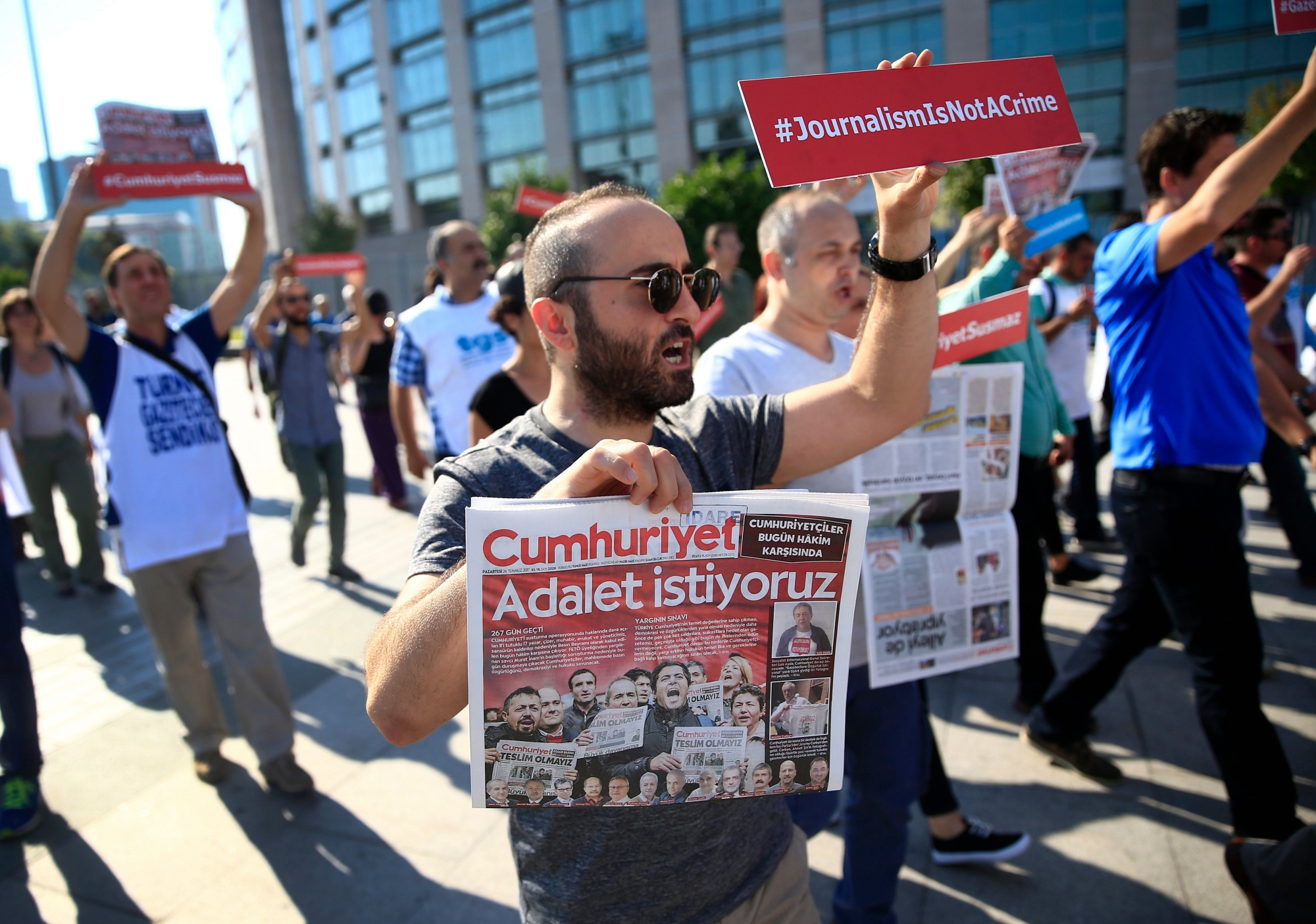 Activists, one holding today's copy of the Cumhuriyet newspaper, march to a court in Istanbul, Monday, July 24, 2017, protesting against the trial of journalists and staff from the newspaper, accused of aiding terror organizations. Journalists and staff from the Turkish newspaper staunchly opposed to President Recep Tayyip Erdogan have gone on trial in Istanbul, accused of aiding terror organizations - a case that has added to concerns over rights and freedoms in Turkey. The newspaper headline reads in Turkish: "We Want Justice."  (AP Photo/Lefteris Pitarakis) Turkey Journalists Trial