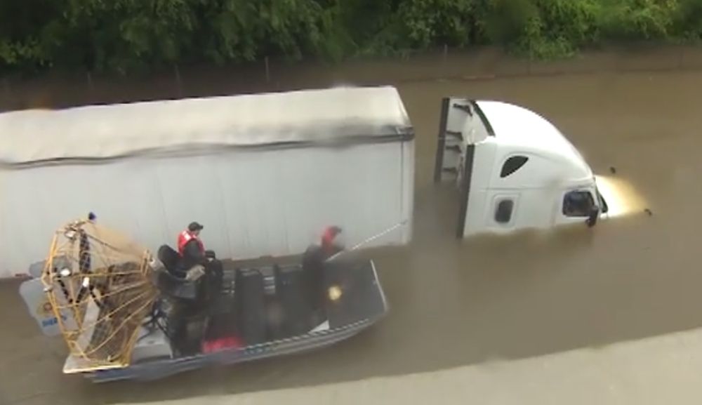 En plein direct, la journaliste aperçoit soudain un camion bloqué par les eaux sur une route en contrebas.
