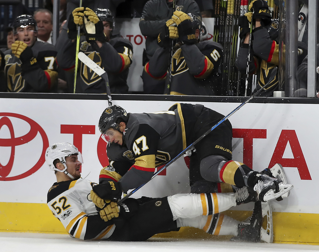 Sean Kuraly, le numéro 52 des Boston Bruins en train de subir la défense ferme de Luca Sbisa des Vegas Golden Knights.