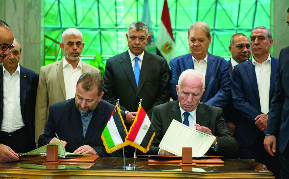 epa06260905 Palestinian member of Fatah Central Committee, Azam al-Ahmed (R), and Hamas deputy head of the politburo Saleh al-Aruri (L) sign an agreement between the two Palestinian factions as Egyptian Intelligence Minister Khalid Fawzi (C, back) looks, in Cairo, Egypt, 12 October 2017. Leaders of both Palestinian factions began met in Cairo for an extended dialogue in order to initiate a mechanism for implementing the reconciliation agreements reached in the last few years.  EPA/MOHAMED HOSSAM EGYPT PALESTINIANS FATAH HAMAS AGREEMENT