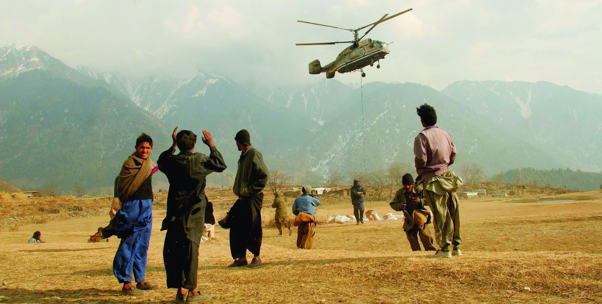 People watch a helicopter from the World Food Program arriving to the village of Paca Biakh in Allai Valley, 70km northwest of Muzaffarabad, Pakistan, Wednesday, Dec. 28, 2005. WFP is delivering food aid to remote villages in high altitude areas isolated by October's earthquake and providing medical care with a local NGO. (KEYSTONE/AP/Tomas Munita) PAKISTAN SOUTH ASIA EARTHQUAKE