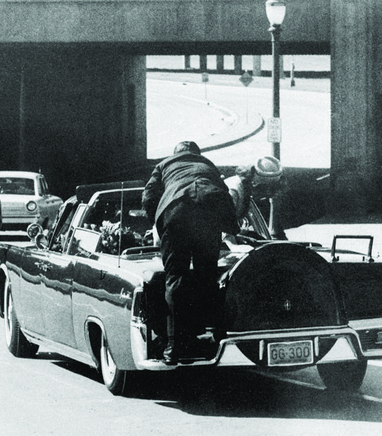 FILE - In this Friday, Nov. 22, 1963 file photo, President John F. Kennedy slumps down in the back seat of the Presidential limousine as it speeds along Elm Street toward the Stemmons Freeway overpass in Dallas after being fatally shot. First lady Jacqueline Kennedy leans over the president as Secret Service agent Clint Hill pushes her back to her seat. "She's going to go flying off the back of the car," Hill thought as he tried to secure the first lady. (AP Photo/James W. "Ike" Altgens) JFK That Awful Day