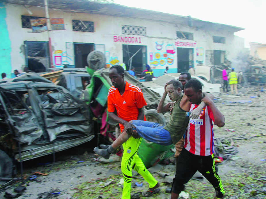 Somalis carry away a man injured after a car bomb was detonated in Mogadishu, Somalia Saturday, Oct 28, 2017.  A suicide car bomb exploded outside a popular hotel in Somalia's capital on Saturday, killing at least 10 people and wounding more than 11, while gunfire could be heard inside, police said. A second blast was heard in the area minutes later. (AP Photo/Farah Abdi Warsameh) Somalia Explosion