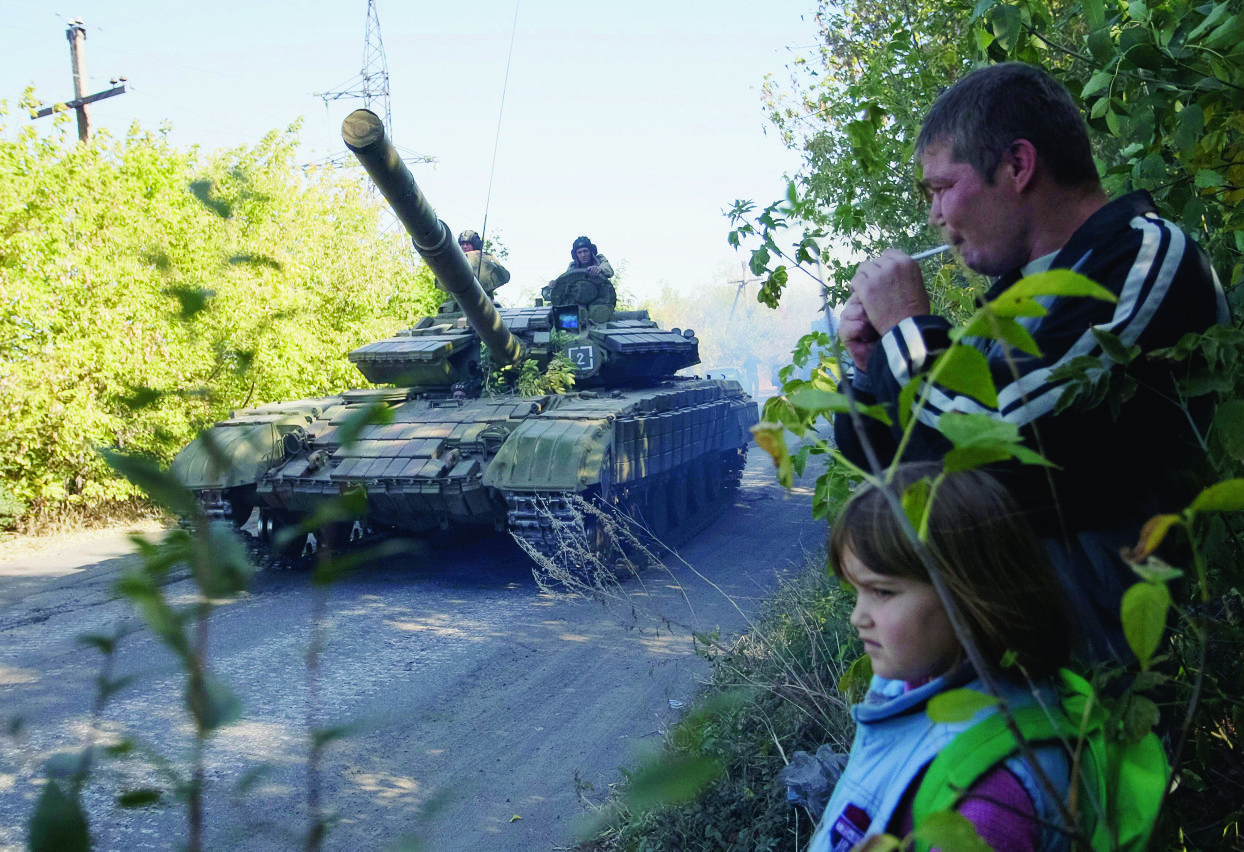epa04961684 A pro-Russian separatist tank drives past locals on a road during, as pro-Russian separatists said, withdrawing their heavy weapons from the front line, in Aleksandrovsk town, near Luhansk, Ukraine, 03 October 2015. Leaders from four countries defended a long-flouted ceasefire agreement for eastern Ukraine on Friday, as withdrawal of small-calibre arms was set to go into effect over the weekend. Ukrainian President Petro Poroshenko said the Ukrainian military would begin withdrawing guns with a calibre of less than 100 millimetres from the front lines on Saturday, describing the agreement as the most significant achievement of the talks. Russian President Vladimir Putin's spokesman, Dmitry Peskov, confirmed that the sides agreed that the withdrawal would begin 'tomorrow at midnight.' While no major breakthroughs were announced after talks lasting nearly five hours, both French President Francois Hollande and German Chancellor Angela Merkel said the region was on the right t