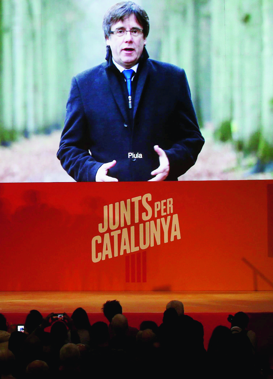 Ousted Catalan president Carles Puigdemont appears on a giant screen during an event of his political platform 'Junts per Catalunya' to mark the official start of the electoral campaign for the Catalan regional election in Barcelona, Spain, Monday, Dec. 4, 2017. Campaigning officially begins at midnight Monday, and in the hours before that moment Catalan pro-independence groups hope to stage protests in front of town halls across the region against the Supreme Court's decision on the detained separatists. (AP Photo/Manu Fernandez) Spain Catalonia