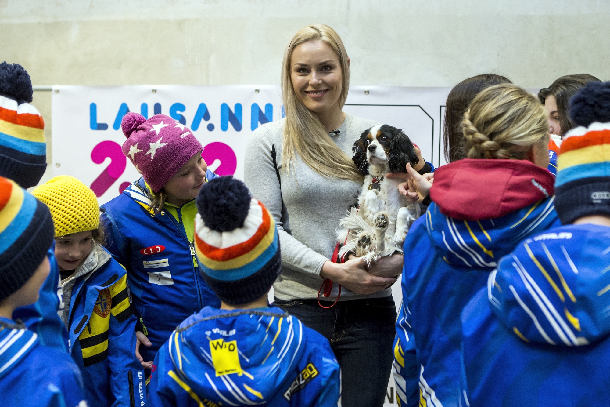 Ski racer Lindsey Vonn from the United States, center, Ambassador for the Winter Youth Olympic Games Lausanne 2020, together with her dog Lucy, poses with kids of the skiing club Alpina, during a press conference in St. Moritz, Switzerland, on Sunday, December 10, 2017. (KEYSTONE/Alexandra Wey)