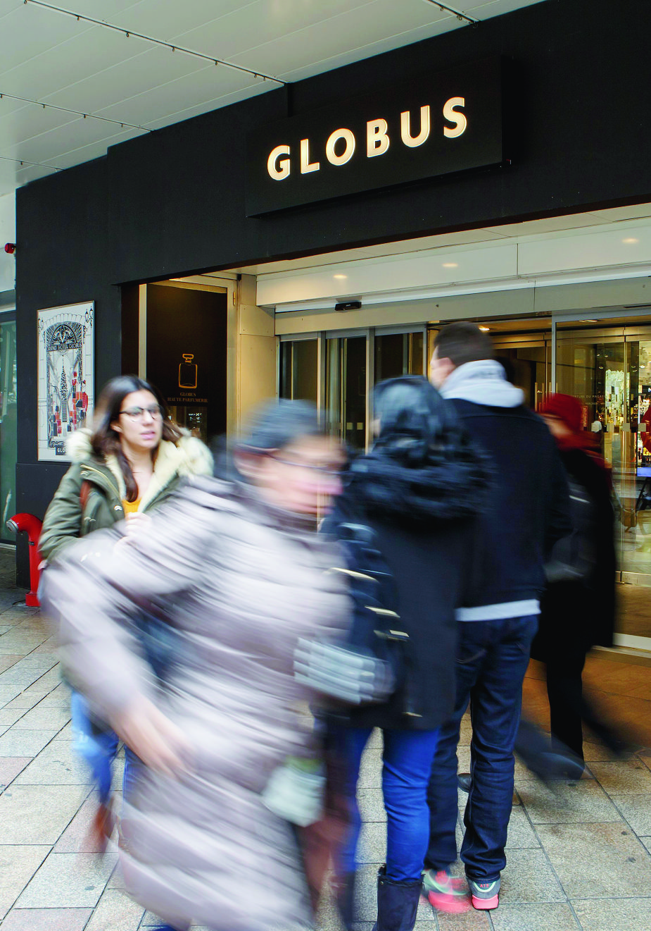 Des personnes entrent ou sortent par l'entree principale de Globus Geneve, ce mercredi 20 decembre 2017 a Geneve. Le grand magasin Globus Geneve mene actuellement une restructuration avec des licenciements depuis quelques mois. (KEYSTONE/Salvatore Di Nolfi) SCHWEIZ GLOBUS SCHILD